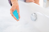 Closeup on young woman adding bath salt in bathtub