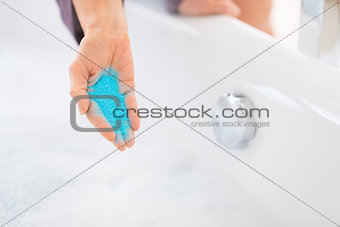 Closeup on young woman adding bath salt in bathtub