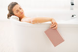Young woman fall asleep while reading book in bathtub