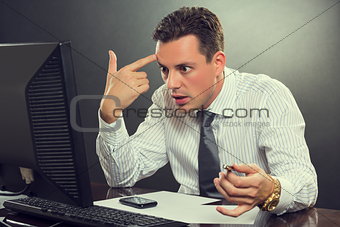 Desperate businessman pointing his finger to his head