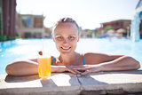 Smiling young woman enjoying a drink in the pool