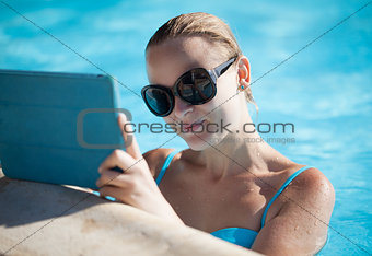 Young woman using a tablet poolside