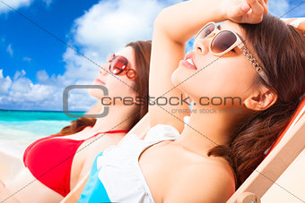 young girls sunbathing and lying on a beach chair