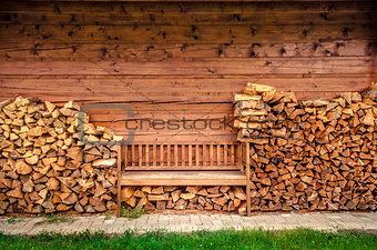Empty wooden bench with pile of firewood