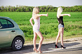 Two sexy blonde girls standing near their broken car and hitchhiking
