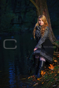 girl sitting on the edge of pond