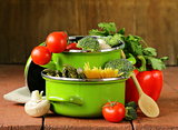 green pots full of vegetables (tomatoes, asparagus, mushrooms, broccoli) and pasta