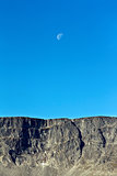 Moon on a background of blue sky and mountains