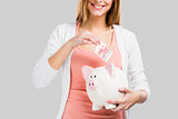 Beautiful woman putting money in a piggy bank