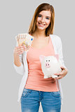 Beautiful woman putting money in a piggy bank