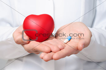 Doctor holding a heart and a pill