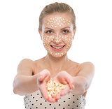 Young woman with oatmeal facial mask showing oatmeal