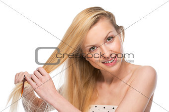 Happy young woman combing hair