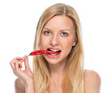 Portrait of teenager eating red chili pepper