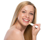Portrait of happy teenager applying hygienic lipstick