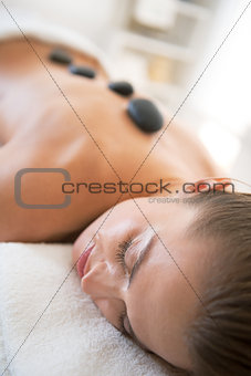 Relaxed young woman laying on massage table and receiving hot st
