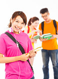 smiling young student holding books and earphone with classmates