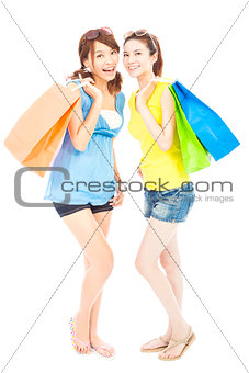  smiling young sisters standing and holding shopping bags