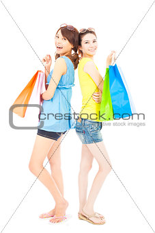  happy young sisters standing and holding shopping bags