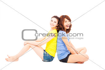two young woman sitting and back to back
