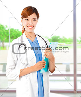 Pretty young female doctor standing and holding document