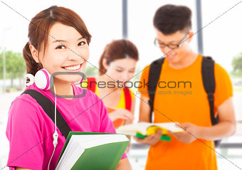 young student holding books and earphone with classmates