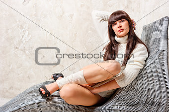 brunette in a comfortable wicker chair sits
