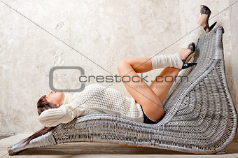 sexy girl resting in a comfortable wicker chair