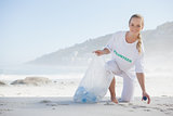 Blonde activist picking up trash on the beach