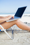 Woman sitting on beach using her laptop