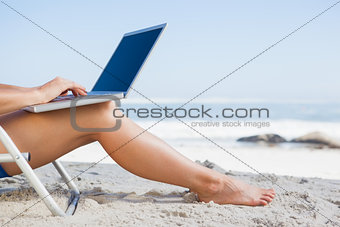 Woman sitting on beach using her laptop