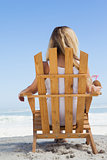 Pretty blonde sitting in deck chair holding coconut drink