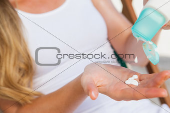 Woman putting sunblock on her hand at the beach