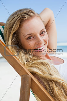 Gorgeous blonde sitting at the beach smiling at camera