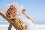Gorgeous blonde sitting at the beach wearing sunhat