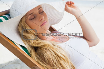 Gorgeous blonde sitting at the beach wearing sunhat