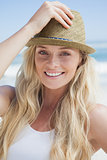 Stylish blonde smiling at camera on the beach