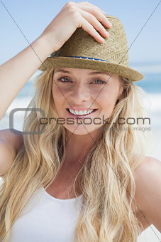 Stylish blonde smiling at camera on the beach