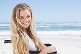 Wheelchair bound blonde smiling at the camera on the beach