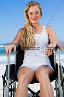 Wheelchair bound blonde sitting on the beach smiling at camera