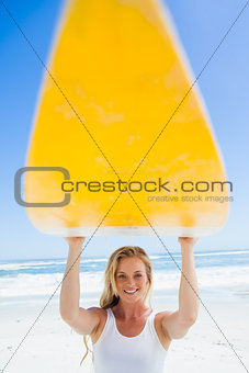 Blonde surfer holding her board smiling at camera