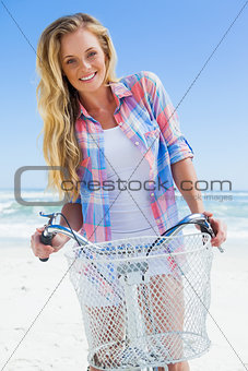 Pretty blonde on a bike ride at the beach smiling at camera