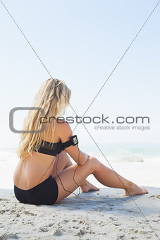 Fit blonde sitting in on the beach taking a break