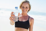 Fit blonde drinking water on the beach