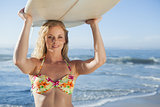 Gorgeous blonde surfer in bikini holding her board