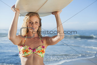 Gorgeous blonde surfer in bikini holding her board