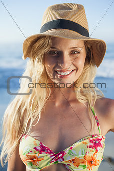 Gorgeous blonde in straw hat smiling at camera on beach