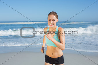 Fit woman smiling and jogging on the beach