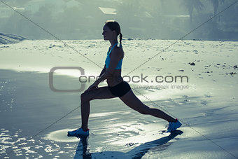 Fit woman doing lunges on the beach