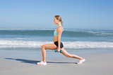 Fit woman doing weighted lunges on the beach